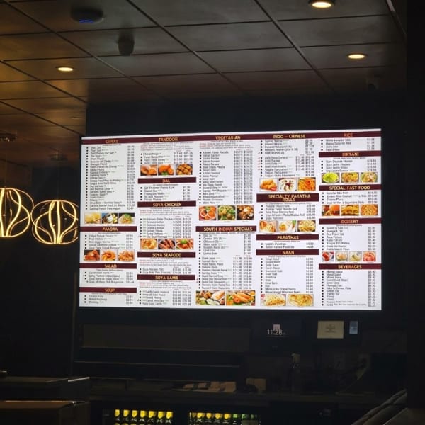 Brightly lit digital menu board displaying an extensive Indian and Indo-Chinese restaurant menu.
