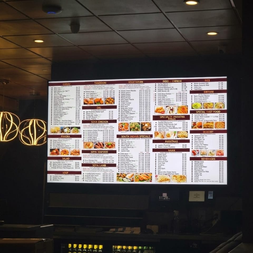 Brightly lit digital menu board displaying an extensive Indian and Indo-Chinese restaurant menu.